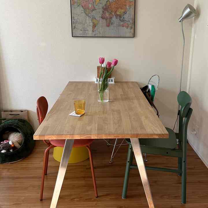 木目調が基調のダイニング、緑と赤の椅子、花瓶にチューリップが飾られた温かみのある雰囲気のあるインテリア