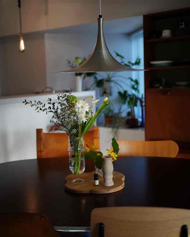 木目調と黒が調和するダイニングルーム、中央のテーブルに花瓶とペンダントライトが配置された雰囲気のある空間