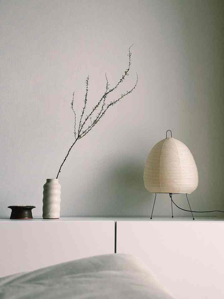 White-toned wall and cabinet featuring natural branch and AKARI lamp in a minimal Japandi style setting