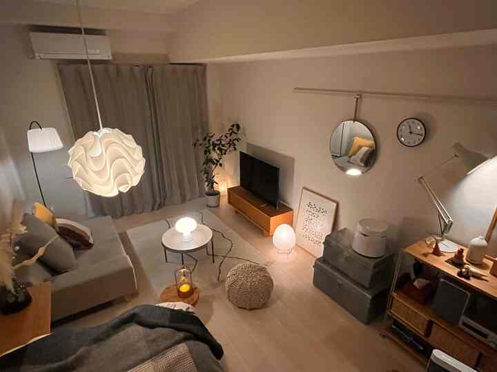 グレーと白のトーンのリビング、ペンダントライトとソファ、テーブルランプが配置された居心地の良い空間