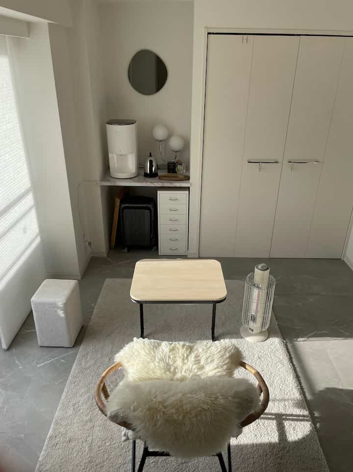 White and gray toned studio apartment featuring compact furniture and simple layout in a minimal interior style