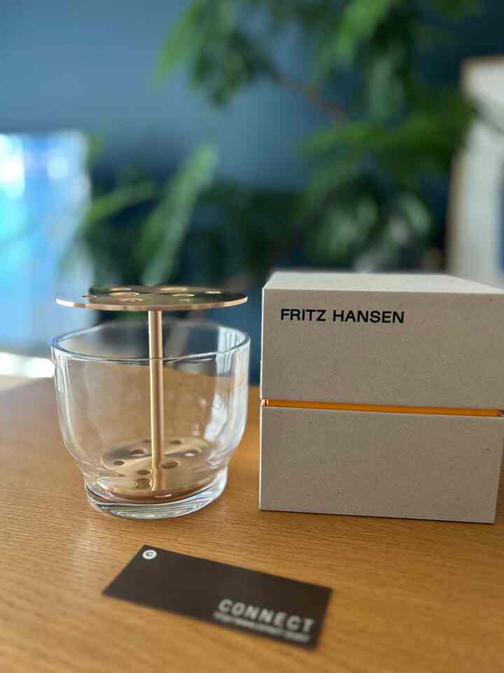 透明なガラスとゴールドの金属が調和したIKEBANAの花器が置かれたシンプルなテーブルのある空間