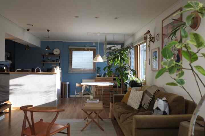 Cozy natural Nordic living room and kitchen with blue walls, wooden furniture, and indoor plants