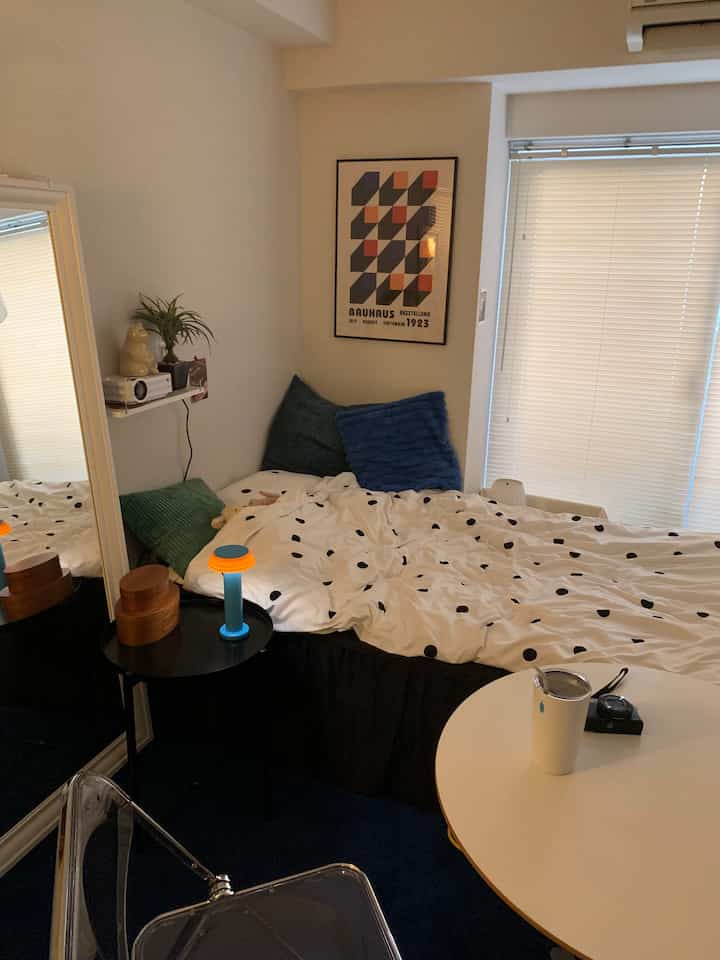 White and navy toned bedroom featuring a bed with pillows, side table, and window blinds creating a cozy atmosphere