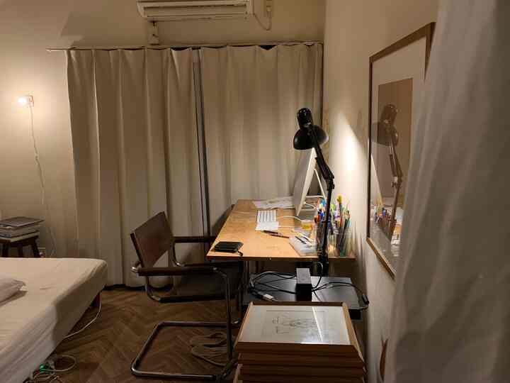 ベージュトーンの寝室兼ホームオフィス、木製デスクとレザー椅子が配置された雰囲気のある空間