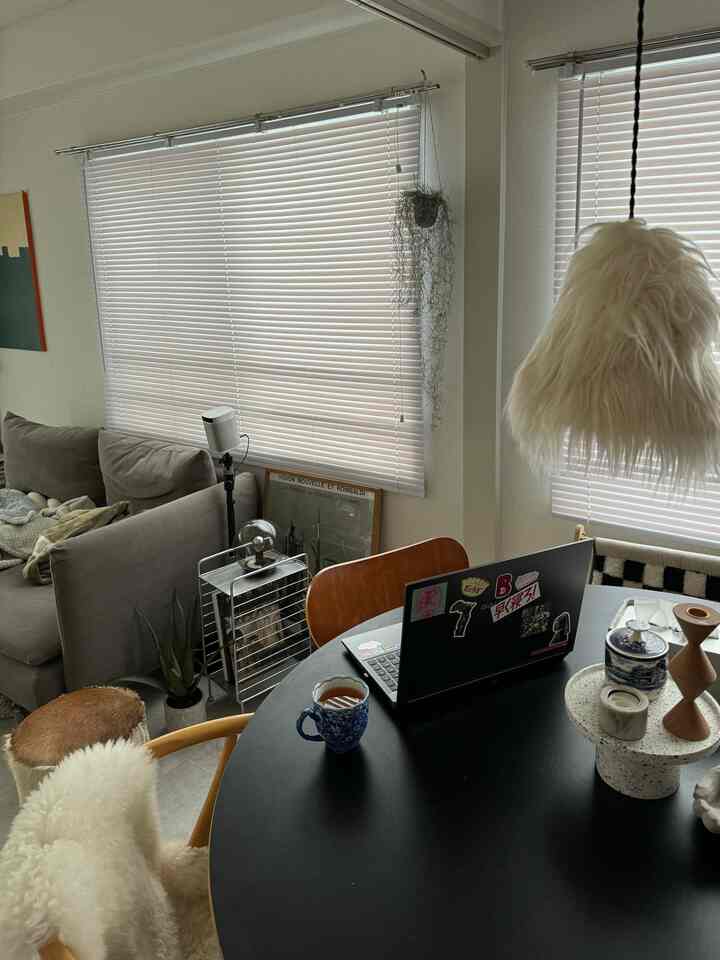 明るいホワイトトーンのミッドセンチュリーモダンな一人暮らしのリビング、シンプルな家具とホームオフィスが調和した空間