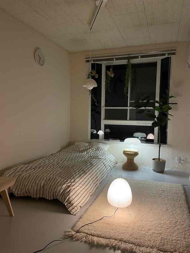 ナチュラルな色調の狭い寝室、フロアランプとテーブルランプが配置された落ち着いた空間