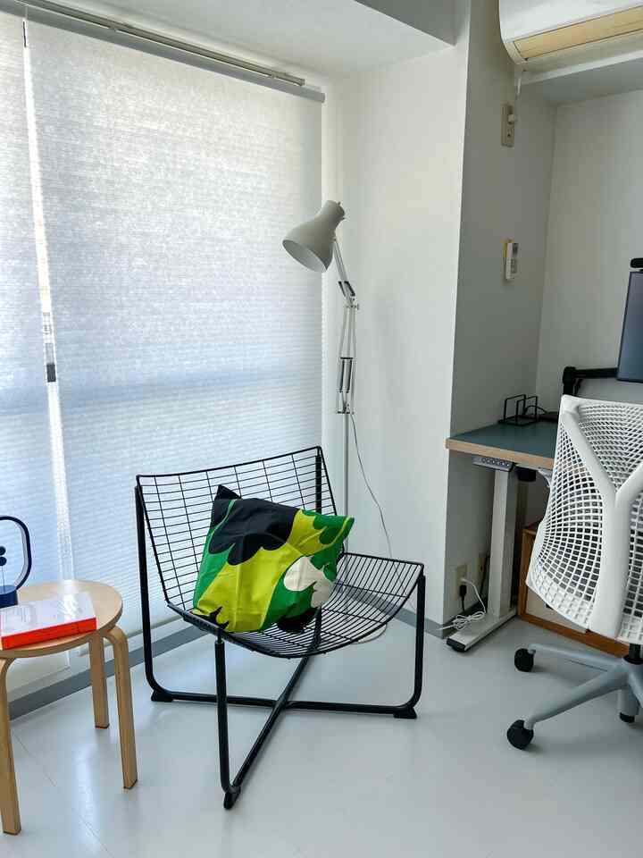 White-toned home office space featuring a black metal chair with cushion, desk, and white blinds with a minimalist feel