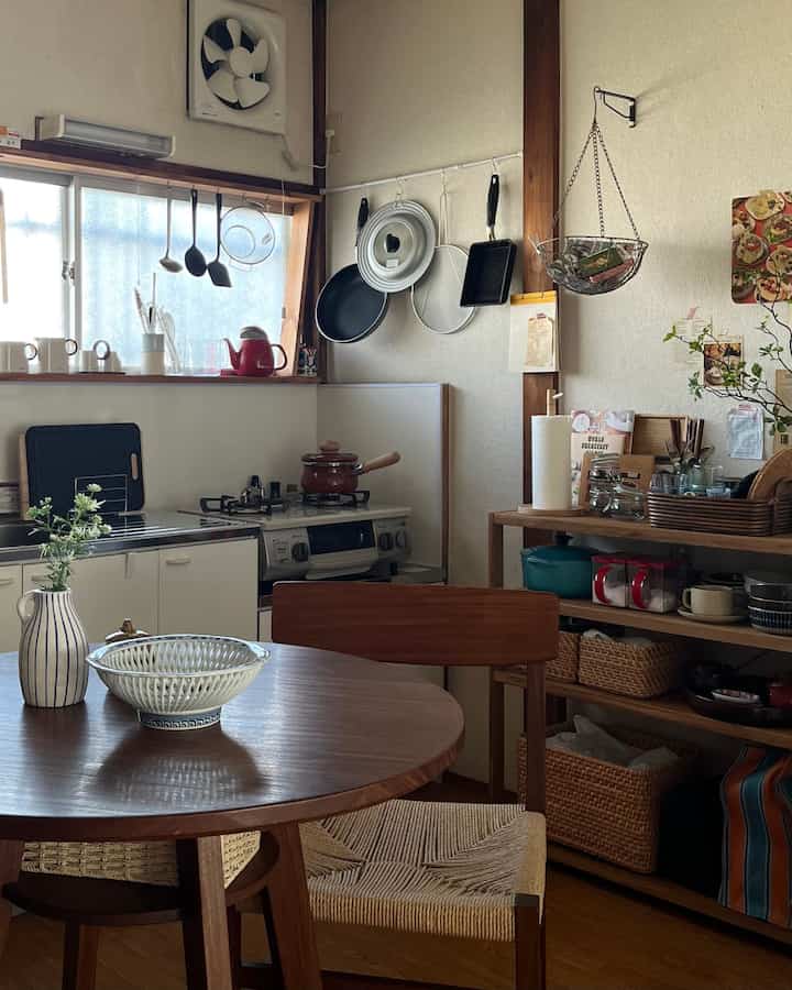 Natural-tone kitchen featuring a wooden dining table and chair, cooking utensils, and storage baskets creating a cozy space