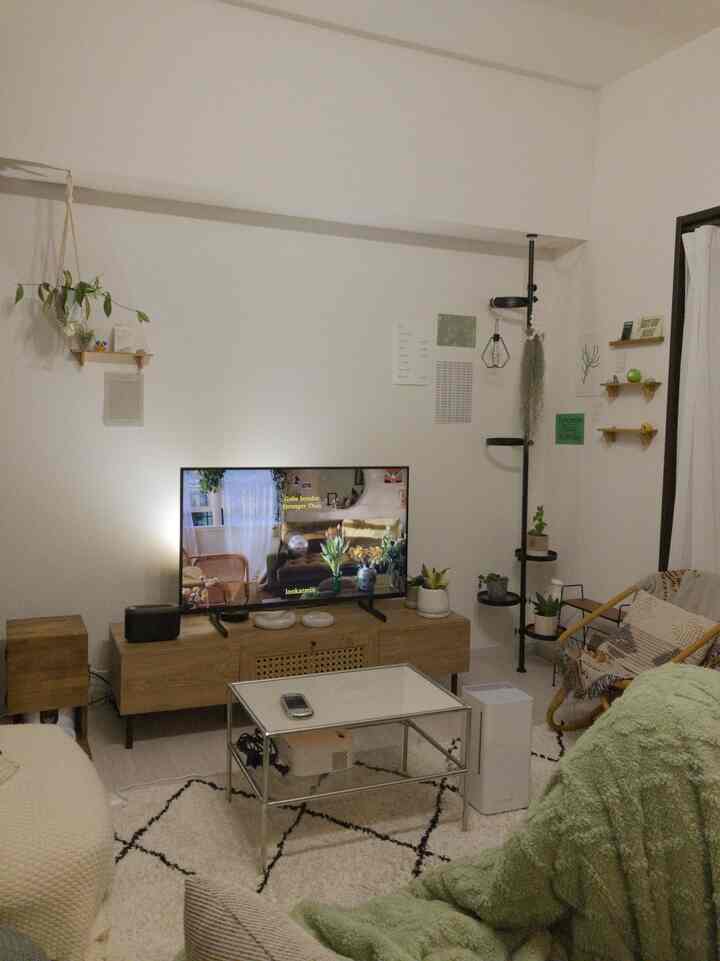 白い壁とブラウンの木製家具が調和した一人暮らしのリビング、ラタンチェアと小さなテーブルが配置された雰囲気のある空間