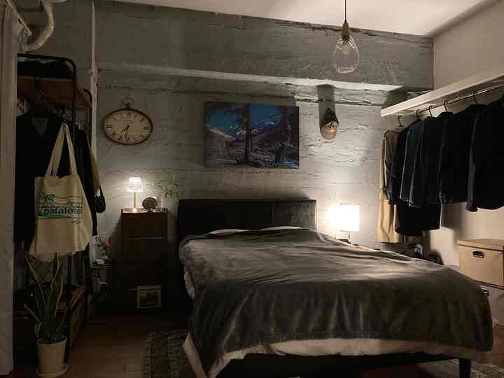 Gray and black toned bedroom featuring a central bed with table lamps on both sides in an industrial style setting