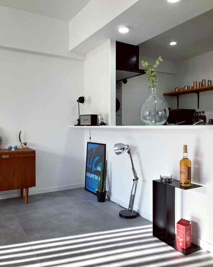 白と茶色のトーンのミッドセンチュリーモダンなキッチンスペース、サイドテーブルとテーブルランプが配置された印象的な空間