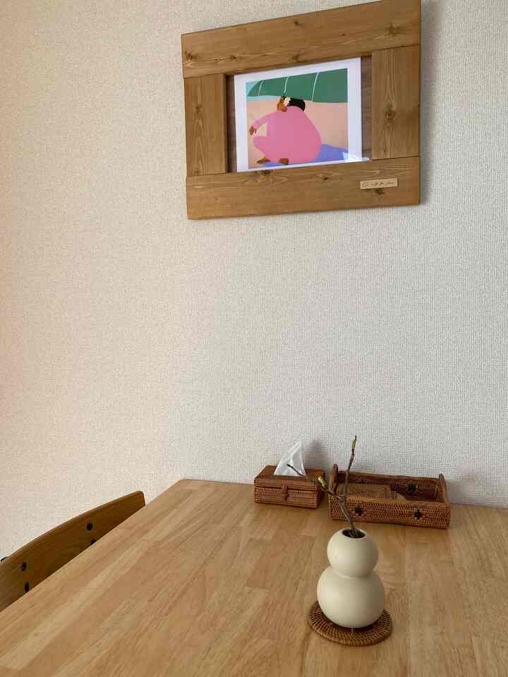 ナチュラルな木目調のダイニングスペース、壁に掛かった木製の額縁アートが印象的な落ち着いた雰囲気のインテリア