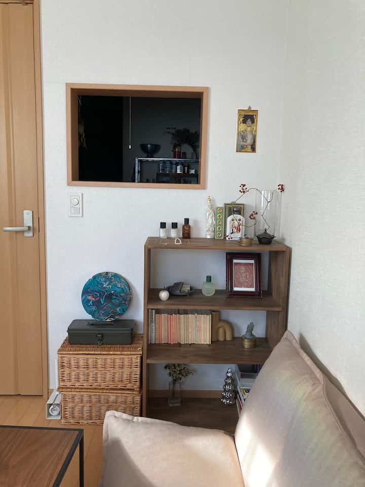 Natural tone wood-tone 7畳 living room featuring a beige sofa and wooden shelves creating a cozy atmosphere