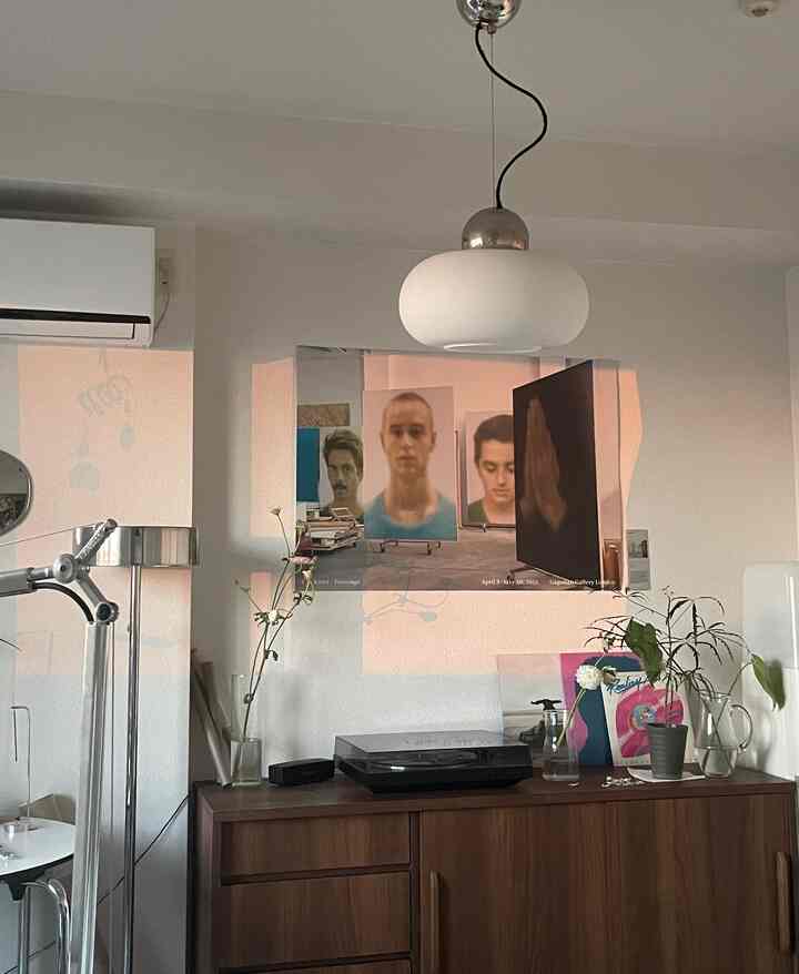 オレンジ色の夕焼けが映るポスターと木製のチェストがあるナチュラルなリビングスペース