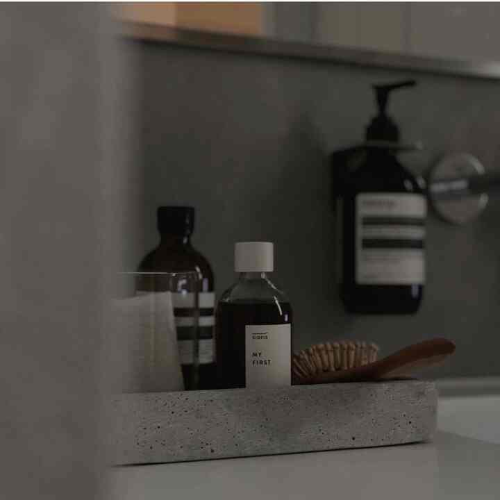 グレーのコンクリート壁を背景に、ナチュラルな木製ブラシが置かれた洗面台のシンプルなインテリア