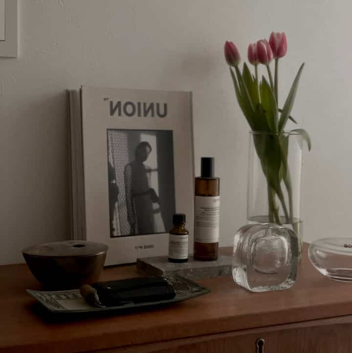 ナチュラルブラウン調の玄関、チューリップの花瓶とアロマ製品が置かれたシンプルなインテリア