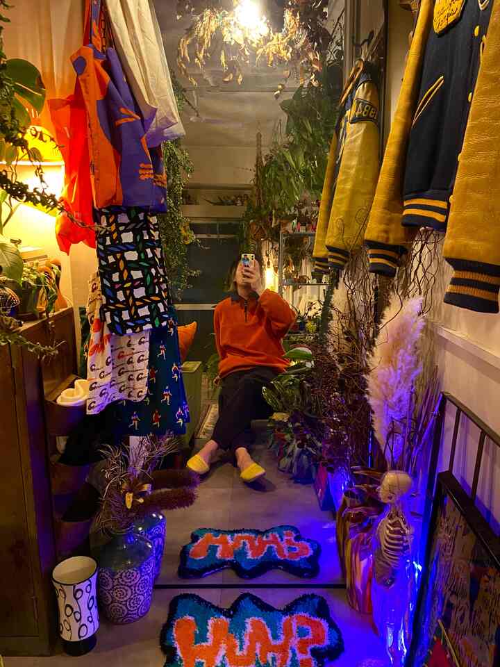 黄色とオレンジ色が印象的な鏡のあるヴィンテージスタイルの衣服と植物が並ぶレトロ感あふれる昭和レトロ空間