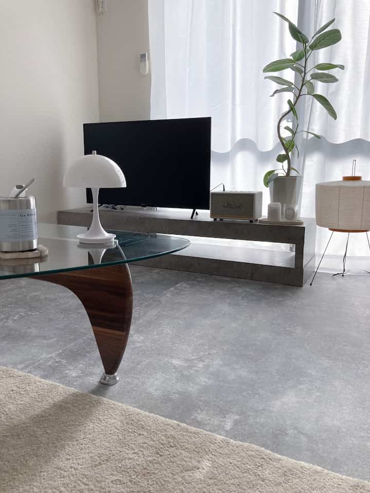 Monotone clean living room featuring a glass coffee table and an Akari style floor lamp with simple natural ambiance
