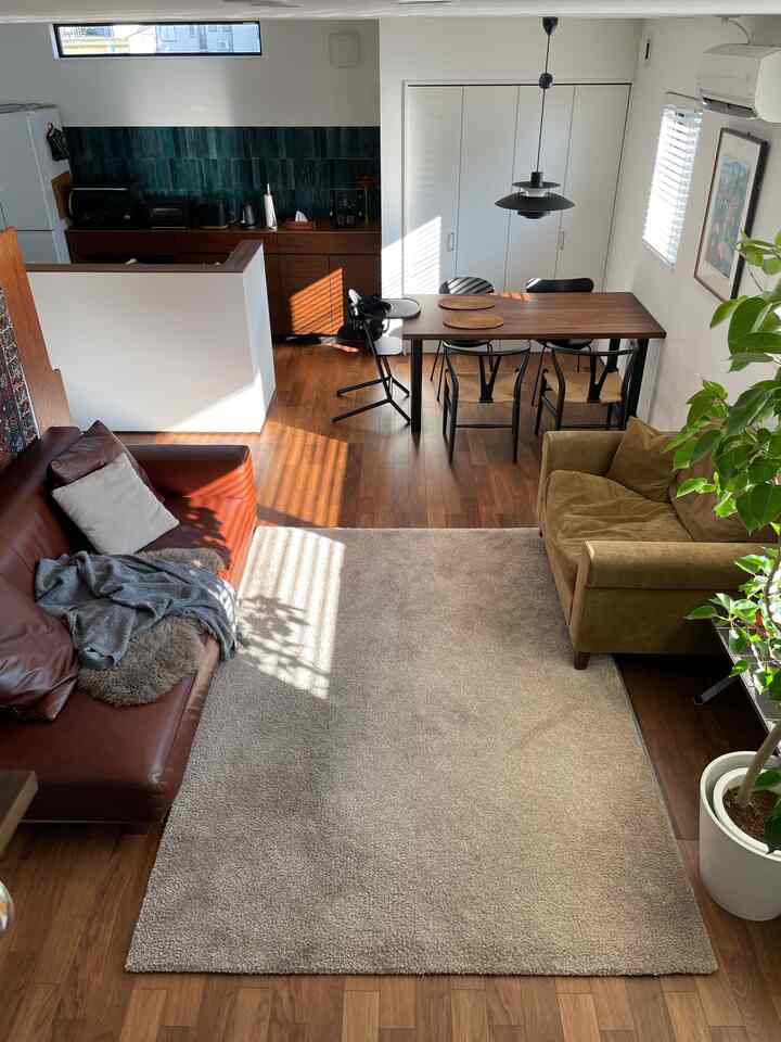 ウッドトーンとブラウンが調和したリビング・ダイニングルーム、ペンダントライトと緑の植物が配置された温かみのある空間