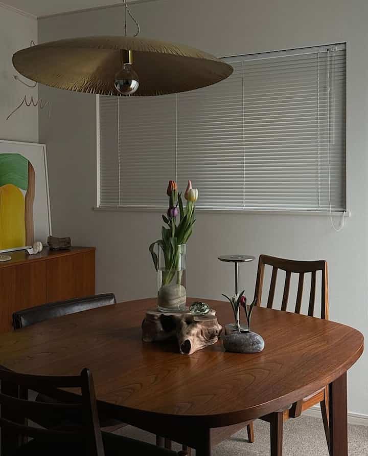 温かみのある木目調のダイニングルーム、木製のダイニングテーブルとチェア、ゴールドのペンダントライトが配置されたナチュラルで落ち着いたインテリア