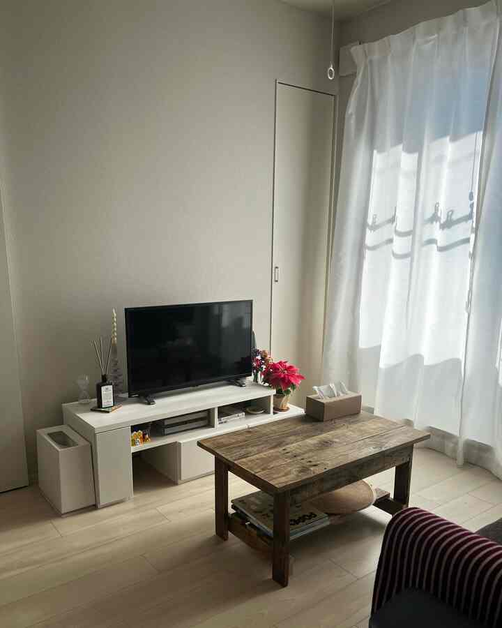 明るい木目調の床と白い家具が配置された、日当たりの良い北欧風のリビングルーム