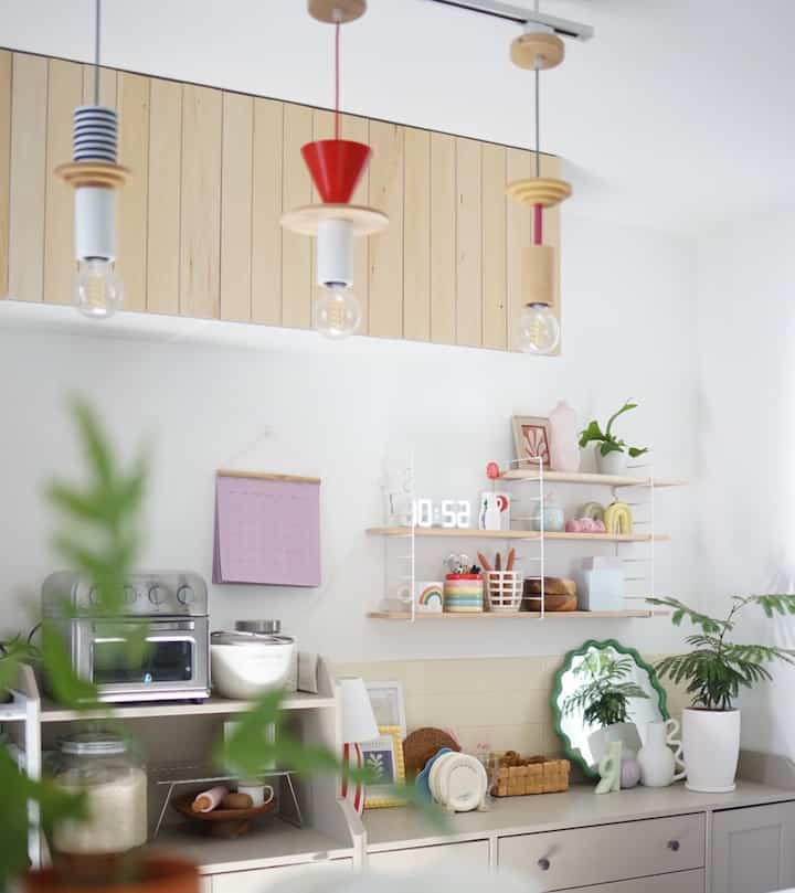 白と木目調の調和が美しいキッチン、植物や色彩豊かな小物が配置された雰囲気のあるインテリア