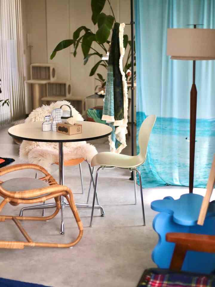 A white and blue-toned dining room featuring mid-century modern chairs and rattan armchair in a clean minimalist space