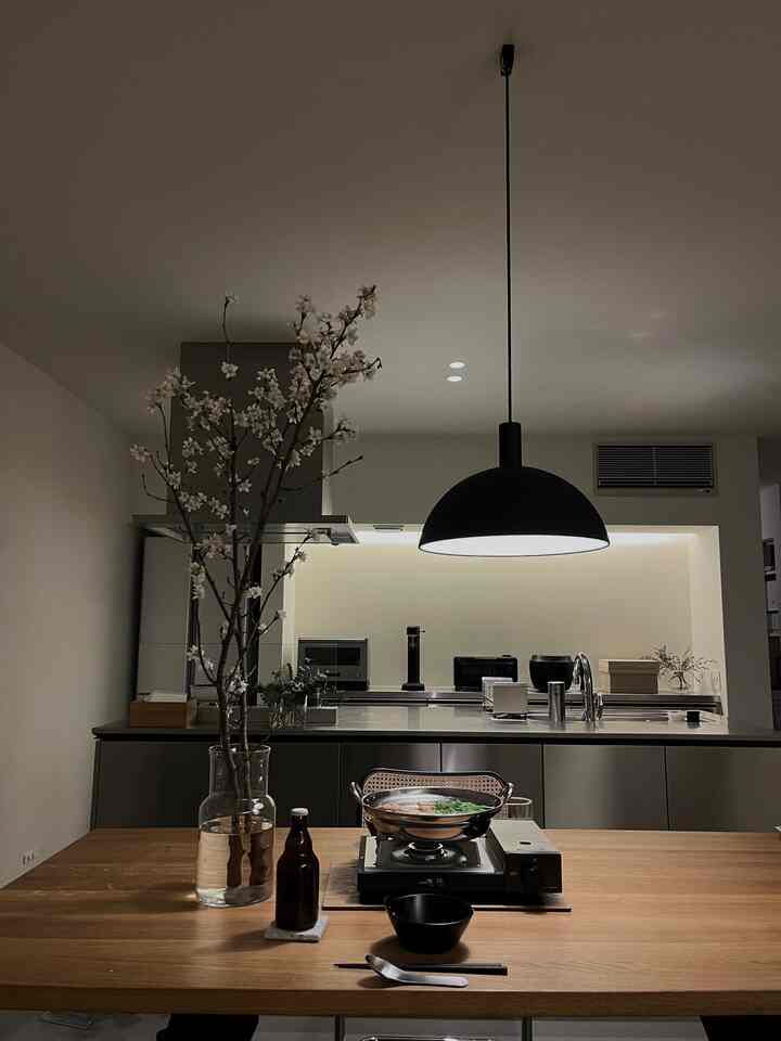 木目調のダイニングテーブルと桜の枝が置かれたモダンなキッチンのインテリア