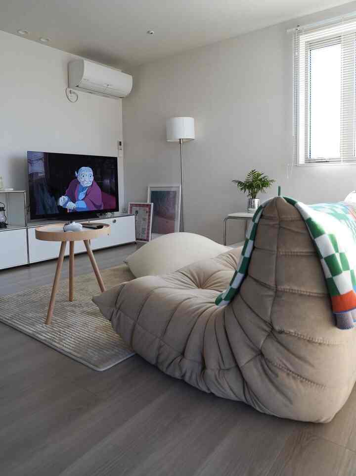 白とベージュのナチュラルモダンなリビング、リクライニングソファとサイドテーブルが配置された印象的な空間