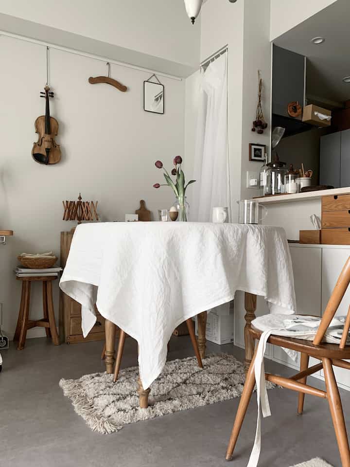 Natural tone 1LDK small dining room featuring wooden dining table and chairs with white tablecloth and flower vase