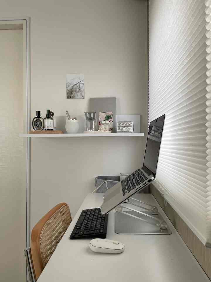 White and natural toned compact home office featuring a desk and blinds in a neat work environment