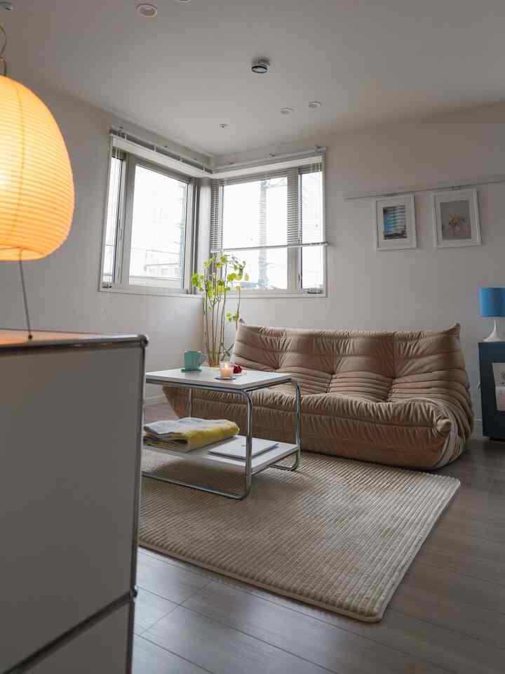 ホワイトとベージュの色調が特徴のリビング、中央にベージュのソファとホワイトのサイドテーブルが配置された雰囲気のある空間