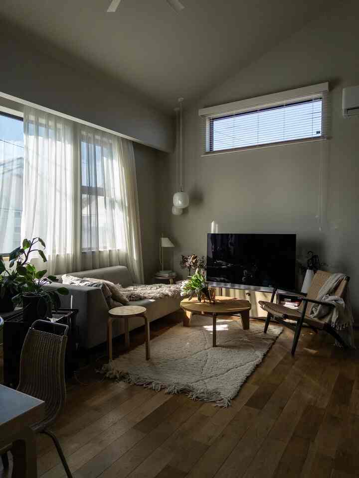 ナチュラルな木目調と白色調のリビング、ソファとアームチェア、丸いコーヒーテーブルが配置された日当たりの良い穏やかな空間