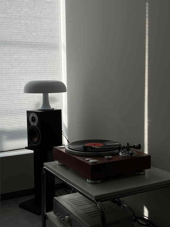 White and brown toned living room music listening space featuring a side table with high-fidelity record player and table lamp