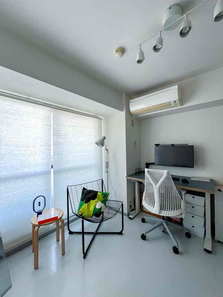 White and black toned small home office featuring a wireframe chair and monitor with a modern and open atmosphere