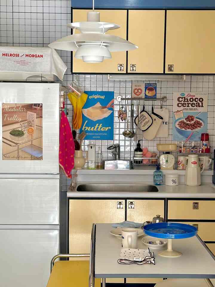 黄色を基調としたキッチン空間、中央にペンダントライトが吊るされ、食器が置かれたテーブルがある雰囲気のあるインテリア