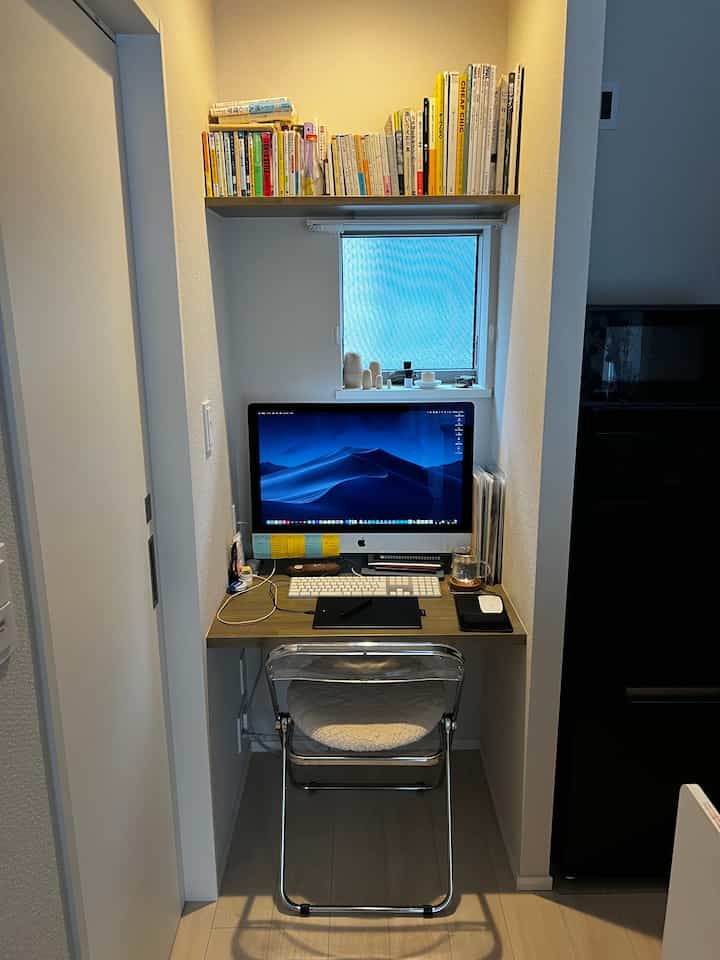 Natural-toned compact workspace featuring bookshelf, wooden desk, and folding chair in a practical setup