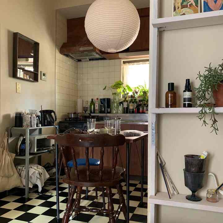 ナチュラルな木目調とベージュの壁が調和したダイニング、チェッカーフロアと植物が雰囲気のある空間