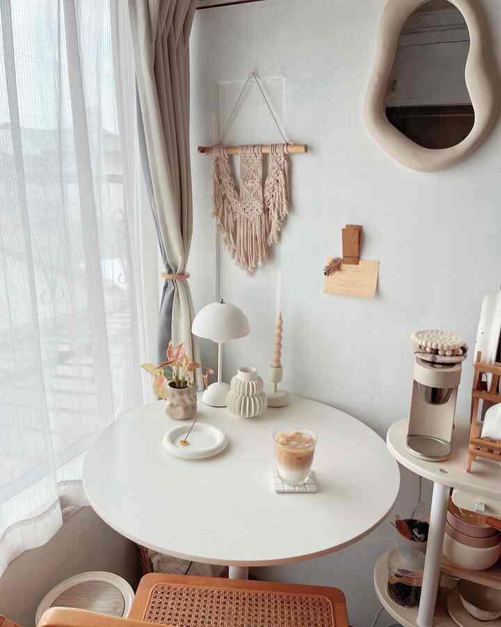 Natural beige and white toned small home cafe featuring a round dining table with a latte and minimalist decor creating cozy atmosphere