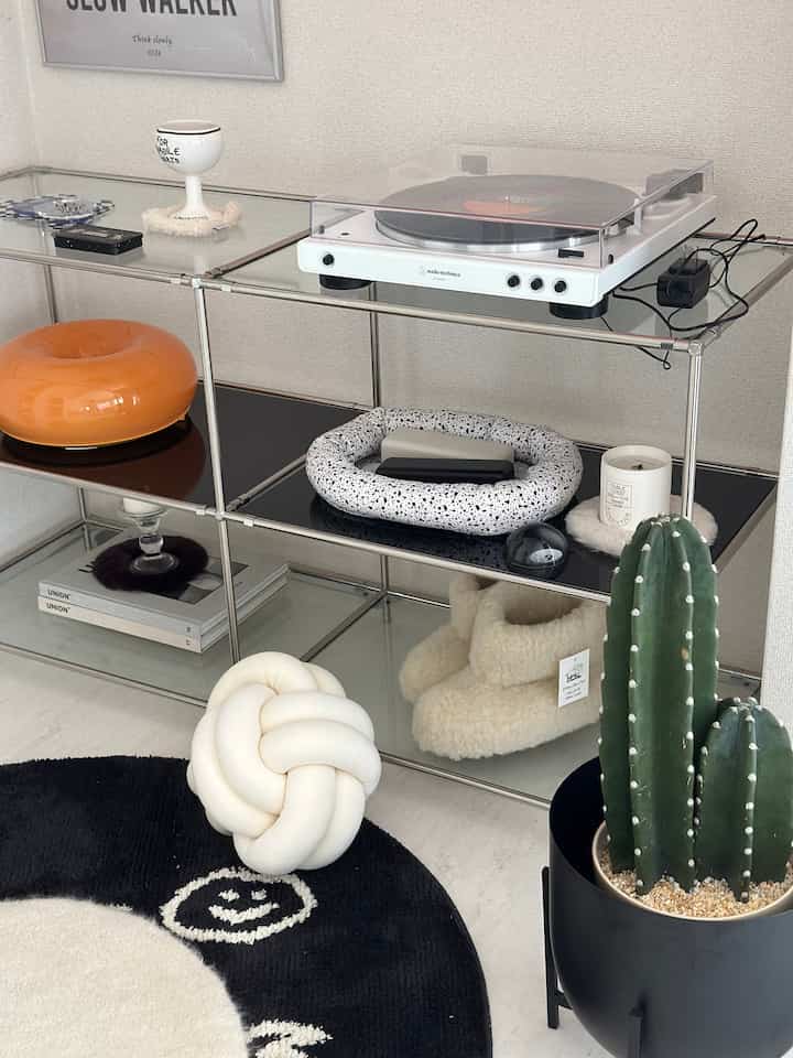 ホワイトとブラックのモノトーンリビング、スチール棚とターンテーブルが配置されたシンプルで現代的な雰囲気のインテリア