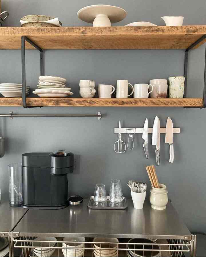 グレーの壁とステンレスの棚、ブラックのカプセルコーヒーマシンと整頓された調理器具があるキッチンのインテリア