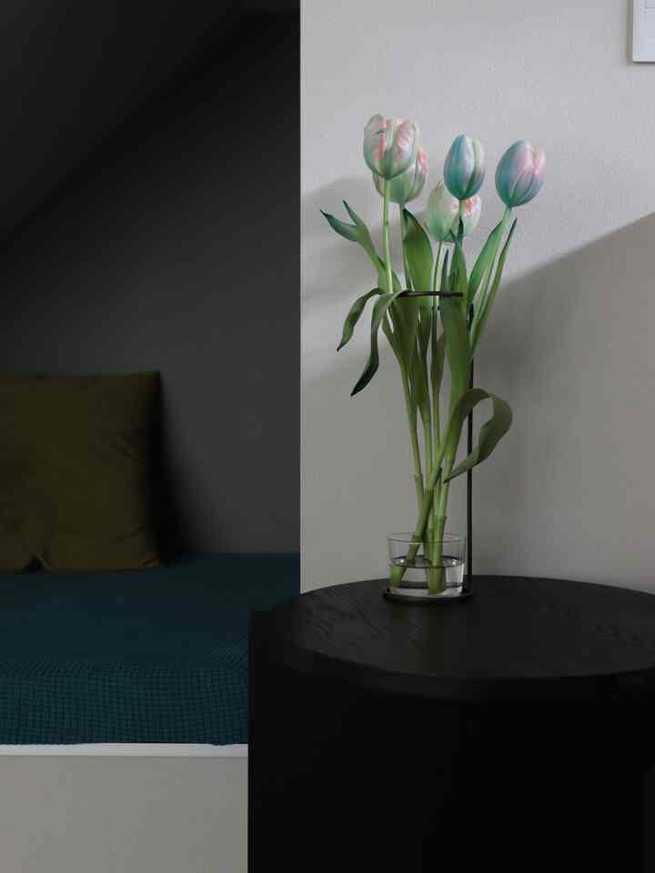 Modern living room with white walls, black side table featuring a transparent vase with tulips