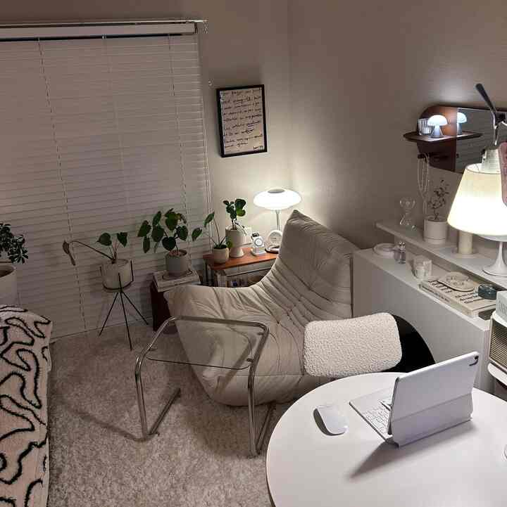 White and beige toned living room featuring a cozy armchair and plants by the window creating a warm atmosphere