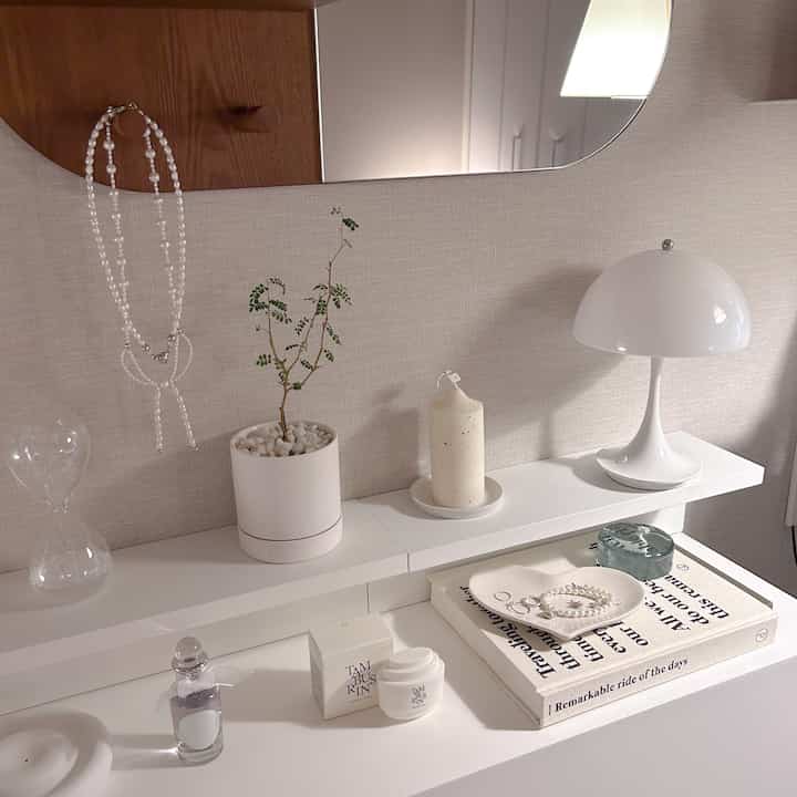 Simple white-toned vanity area featuring a heart-shaped tray and a mushroom-style table lamp with clean decor