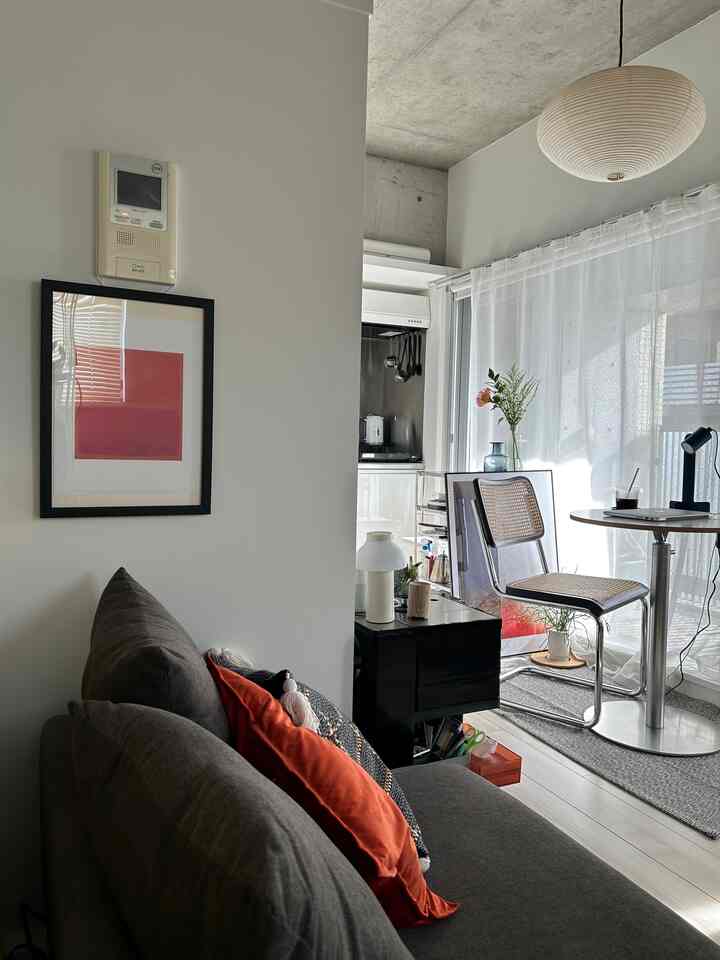 White-walled studio apartment featuring a brown sofa and simple, cozy compact living area