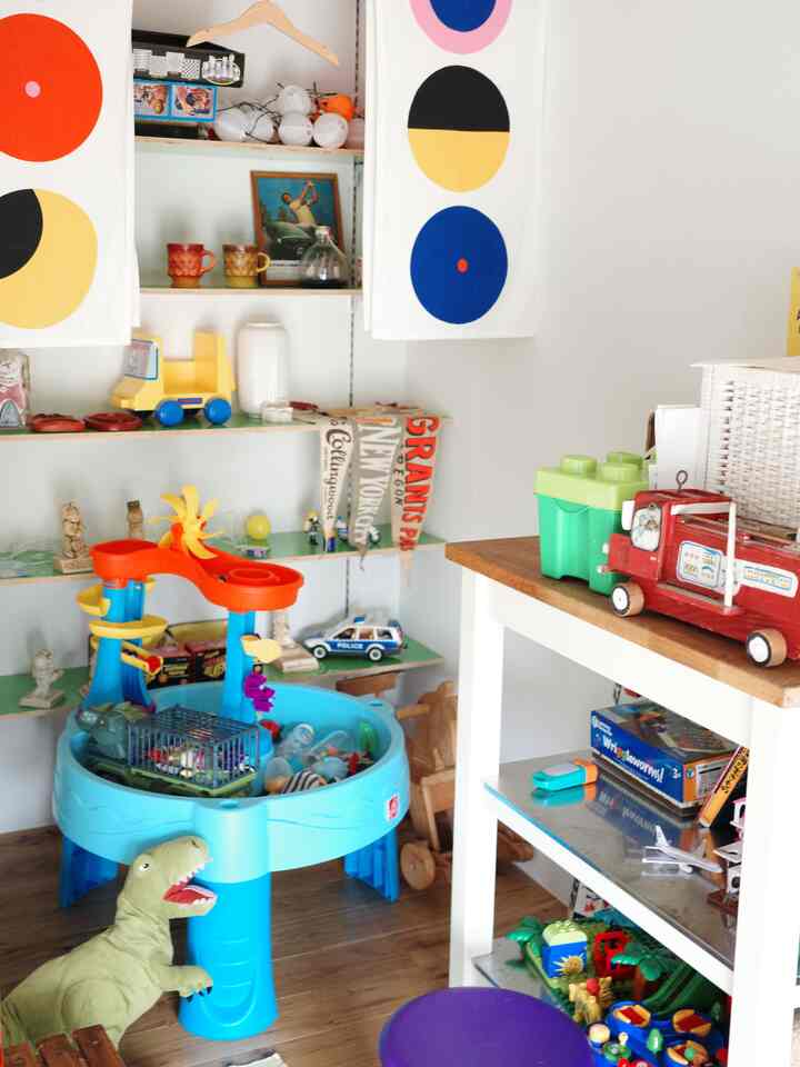 Natural wood floor and white walls in kids' room featuring colorful toys and a bright blue play table creating cozy atmosphere