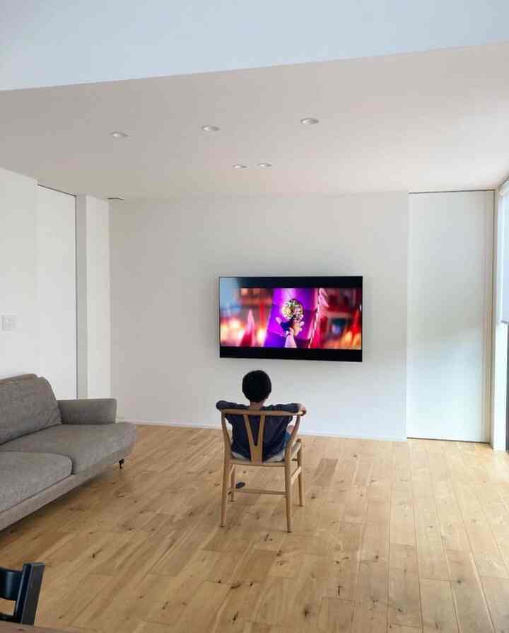 白い壁と木目調の床のリビング、中央のCH24 Yチェアに子供が座ってテレビを見るシンプルでモダンな空間