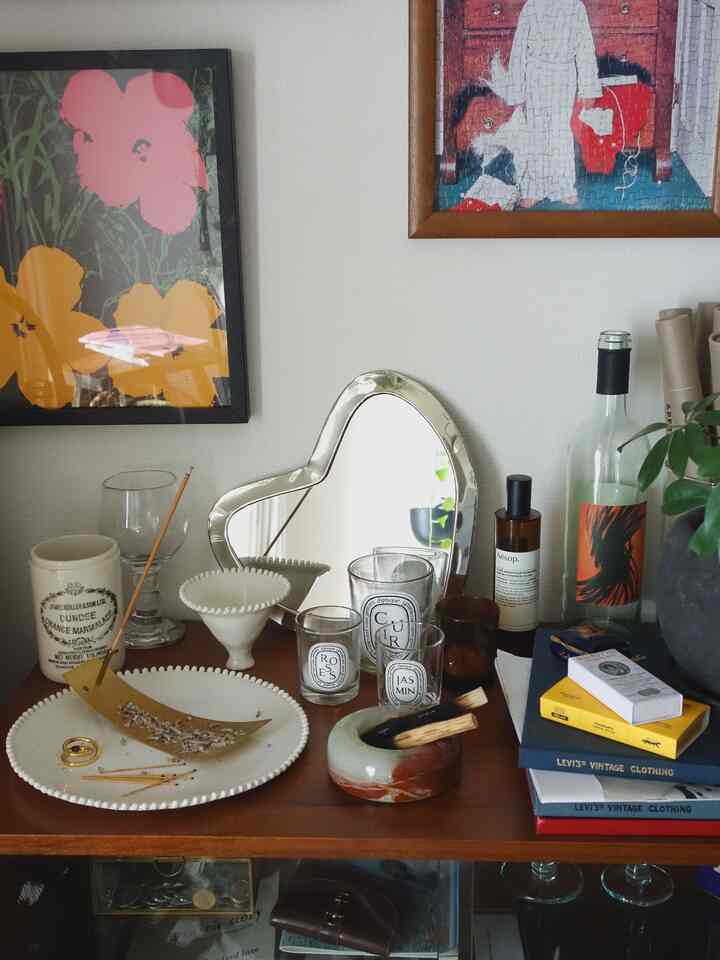 茶色の落ち着いたリビング、ハート形の卓上ミラーと多様なキャンドル、インセンスホルダーが配置された雰囲気のある空間