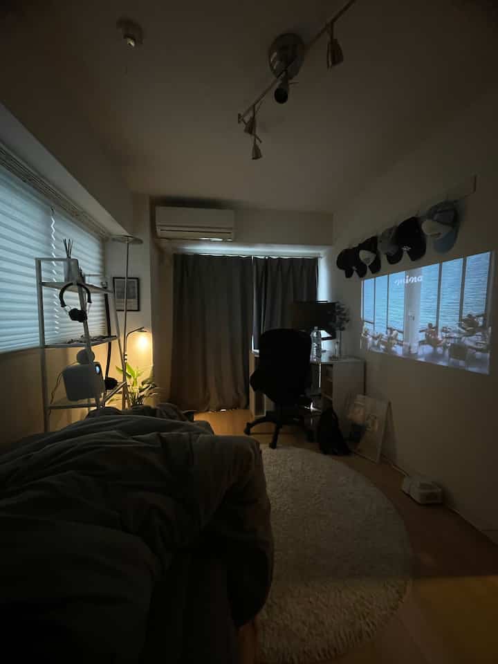 Gray and white toned studio apartment bedroom featuring compact layout with bed and desk in a modern home office space
